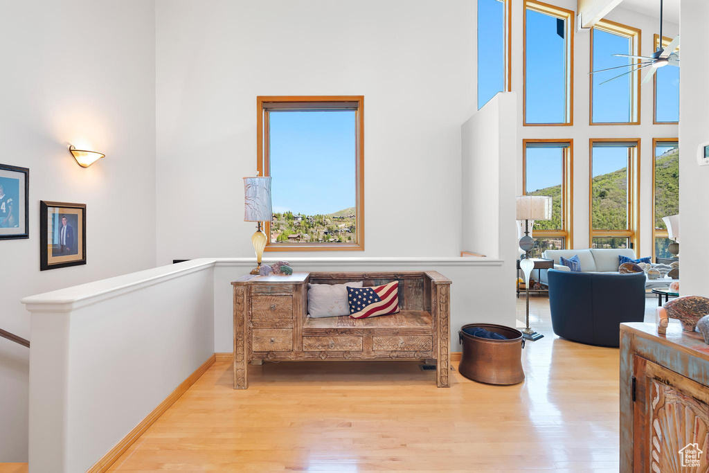 Sitting room with wood finished floors, an upstairs landing, a high ceiling, and baseboards