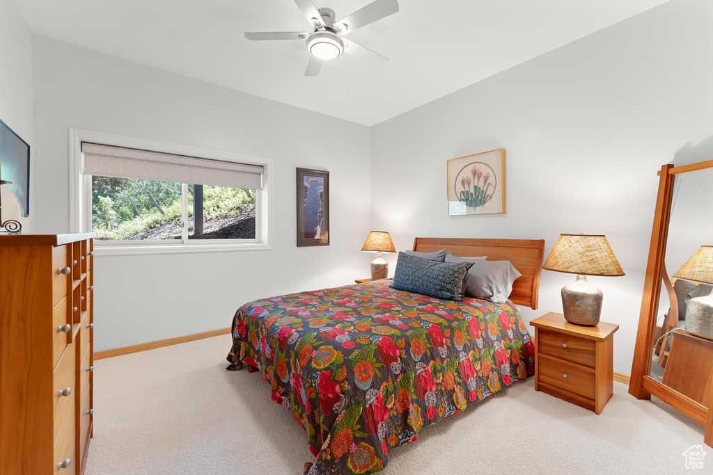 Bedroom with light carpet, baseboards, and ceiling fan