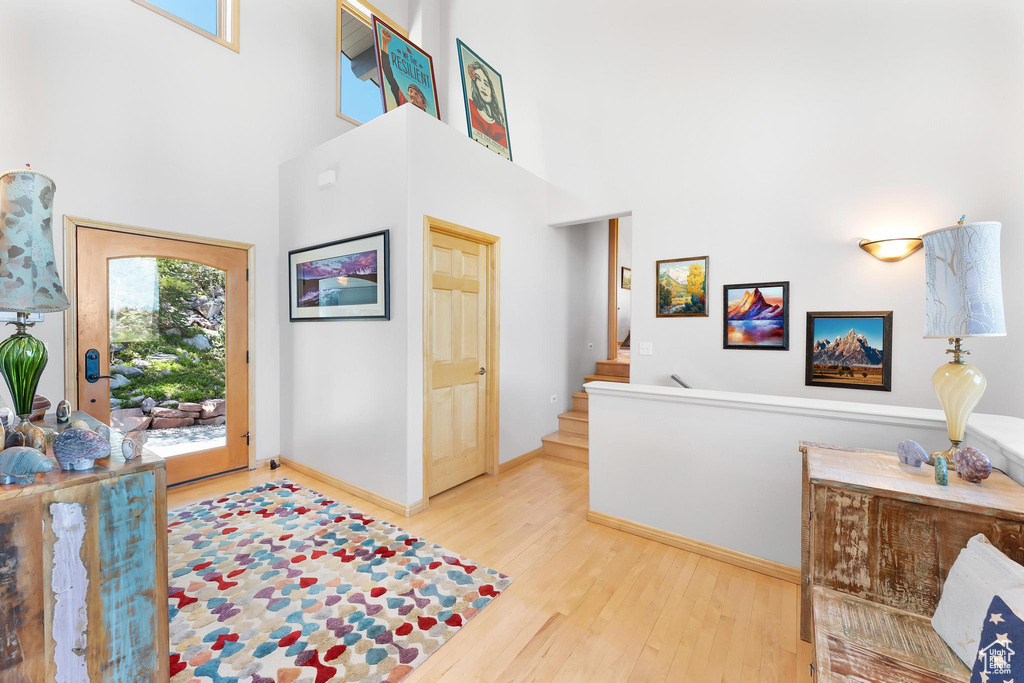 Foyer entrance with a towering ceiling, wood finished floors, stairs, and baseboards
