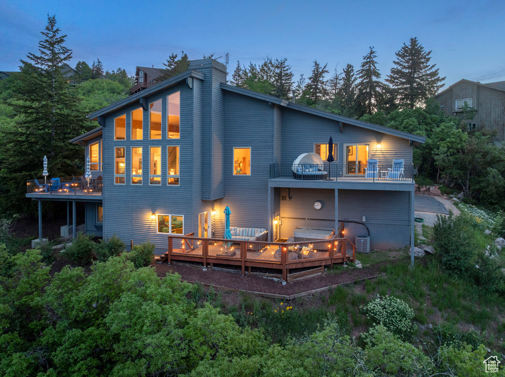 Back of house with a balcony, a wooden deck, cooling unit, and a chimney
