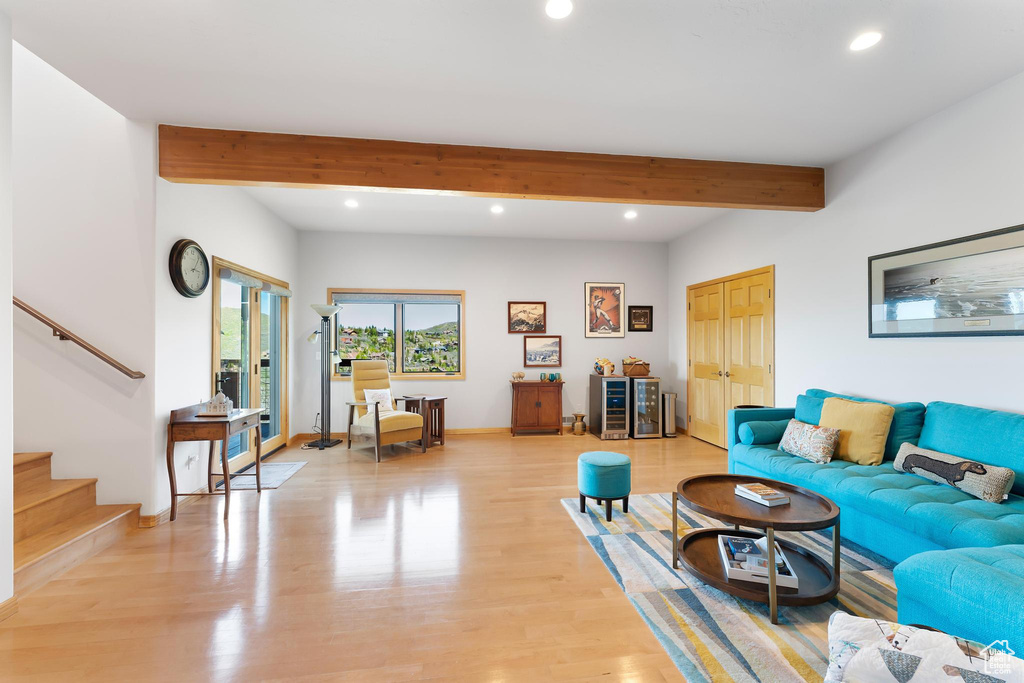 Living room with recessed lighting, beam ceiling, stairs, light wood-style flooring, and baseboards