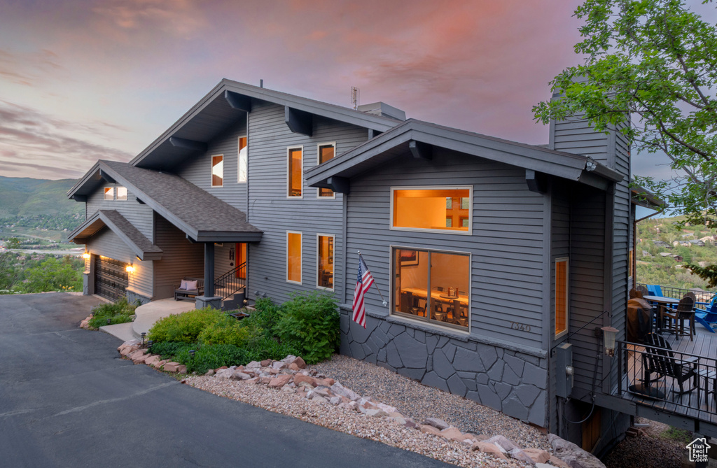 Modern home featuring a chimney, a garage, and asphalt driveway