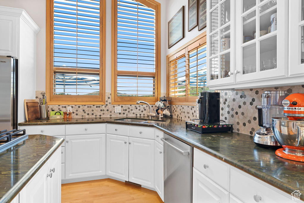 Kitchen with appliances with stainless steel finishes, a sink, decorative backsplash, and glass insert cabinets