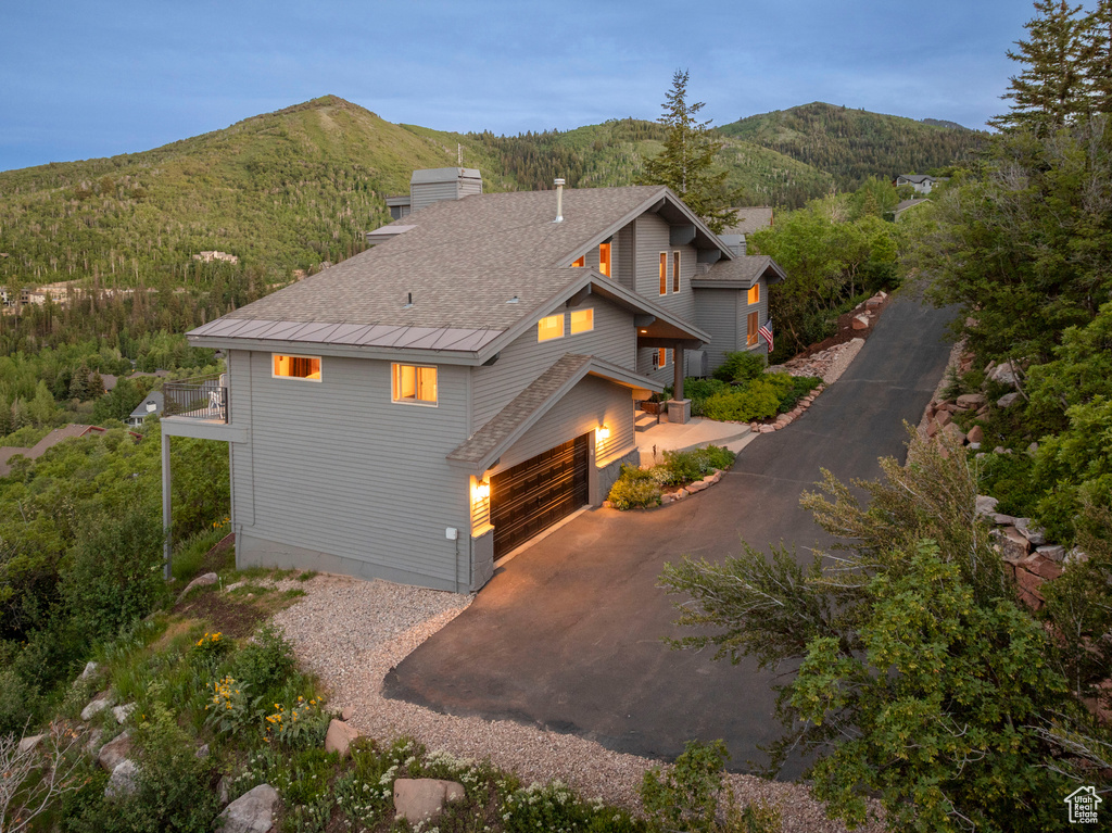 View of home\'s exterior with driveway, a mountain view, an attached garage, and a shingled roof