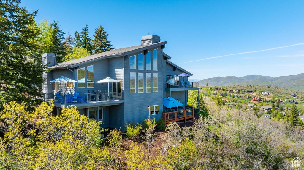 Rear view of house with a chimney, a mountain view, and a balcony