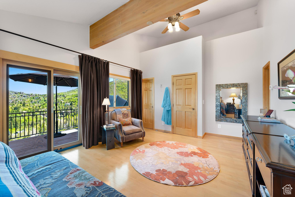 Bedroom featuring access to exterior, a towering ceiling, light wood finished floors, and baseboards