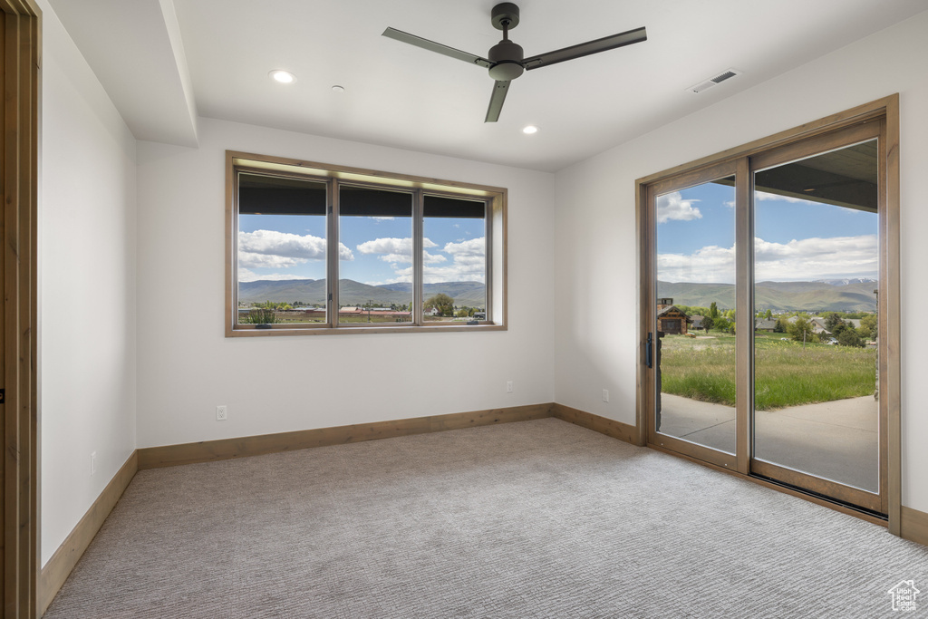 Carpeted spare room featuring a mountain view, ceiling fan, recessed lighting, and baseboards