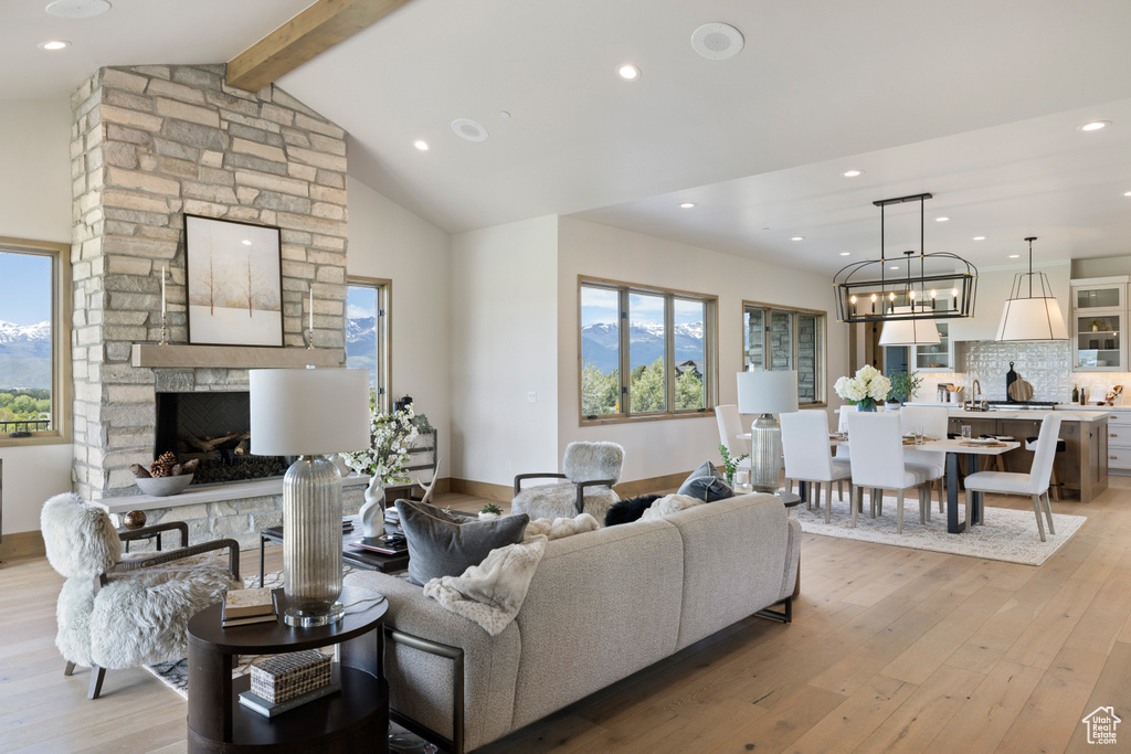 Living room featuring light wood-style floors, plenty of natural light, a stone fireplace, recessed lighting, and baseboards