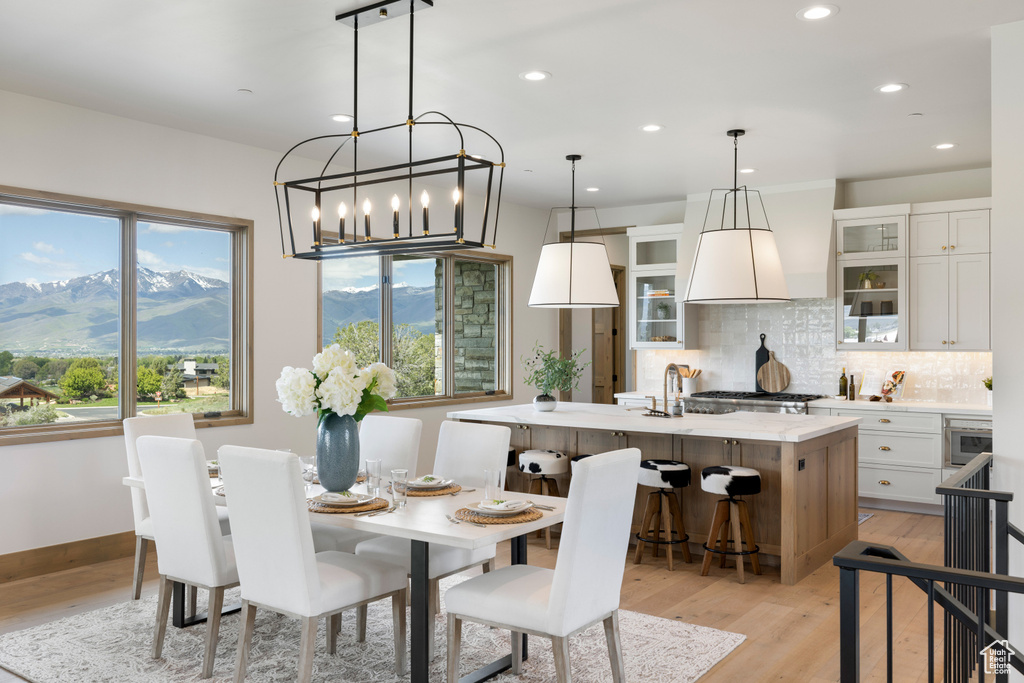 Dining space with light wood-type flooring, recessed lighting, a mountain view, a chandelier, and baseboards