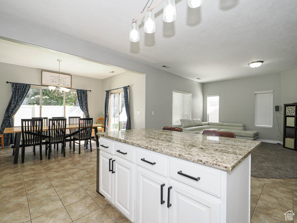 Kitchen featuring a chandelier, white cabinetry, open floor plan, pendant lighting, and a center island