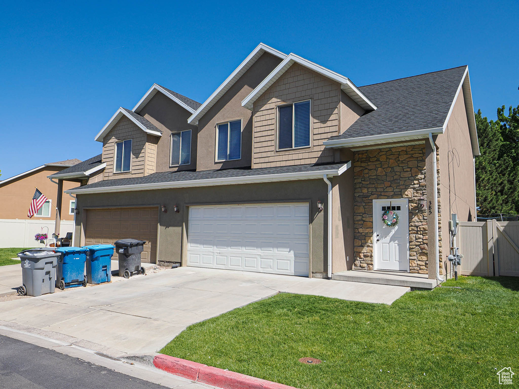 View of front of home featuring stone siding, an attached garage, driveway, roof with shingles, and stucco siding