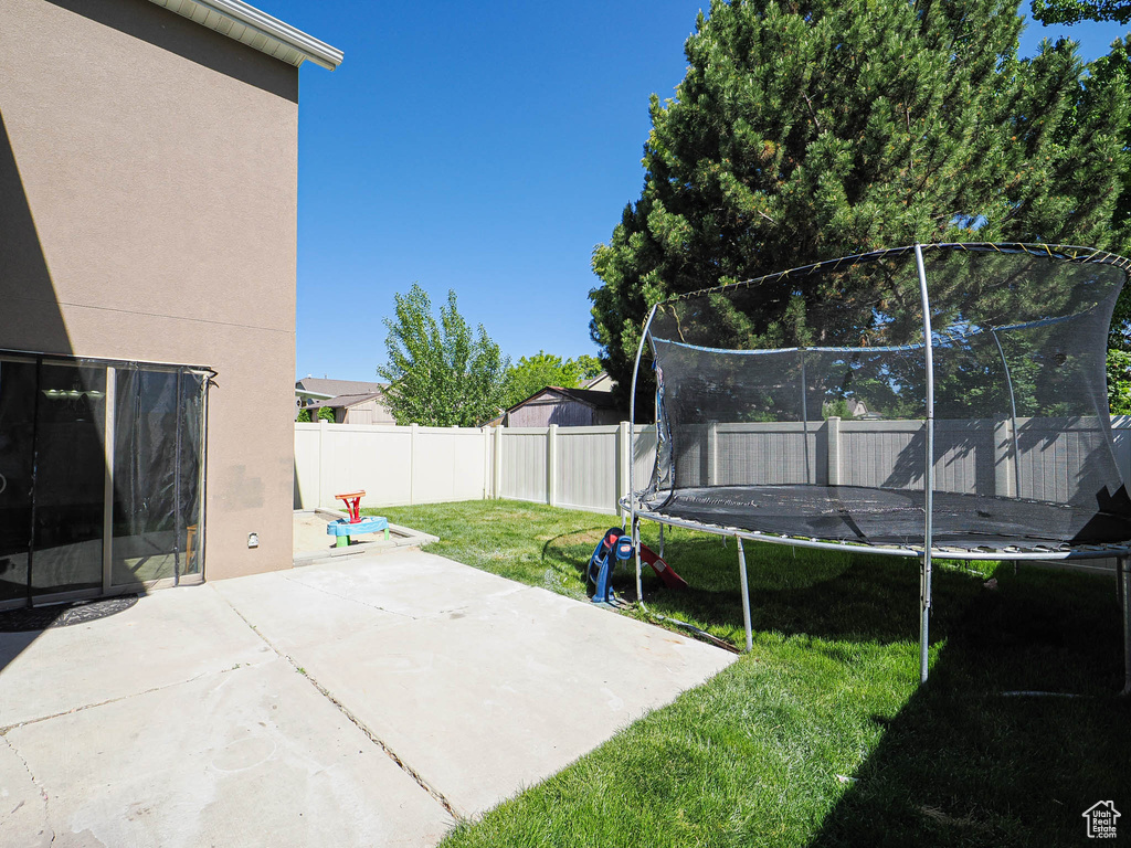 View of yard with a trampoline and a patio