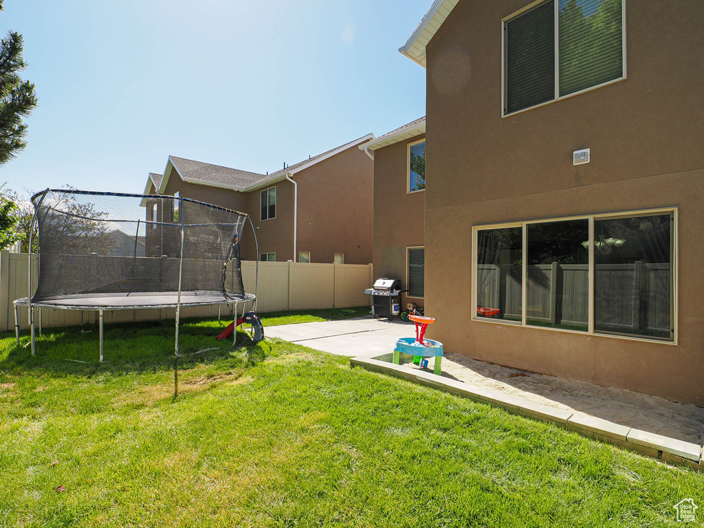 View of yard featuring a trampoline and a patio