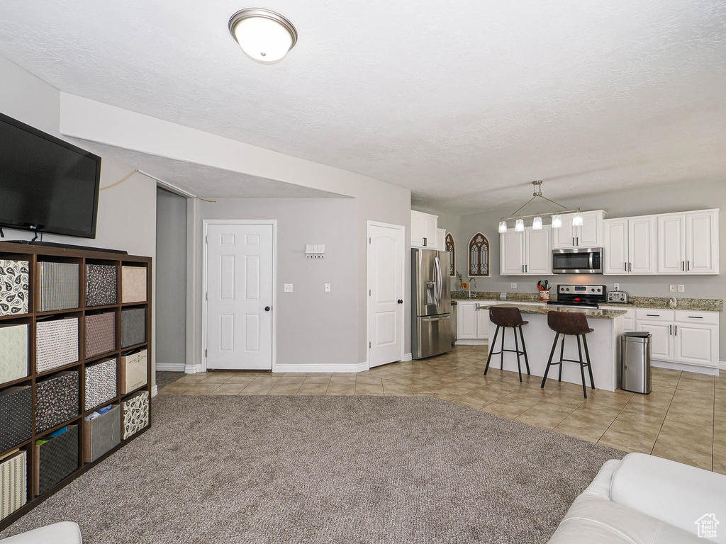 Living area with baseboards, light tile patterned floors, a textured ceiling, and a chandelier