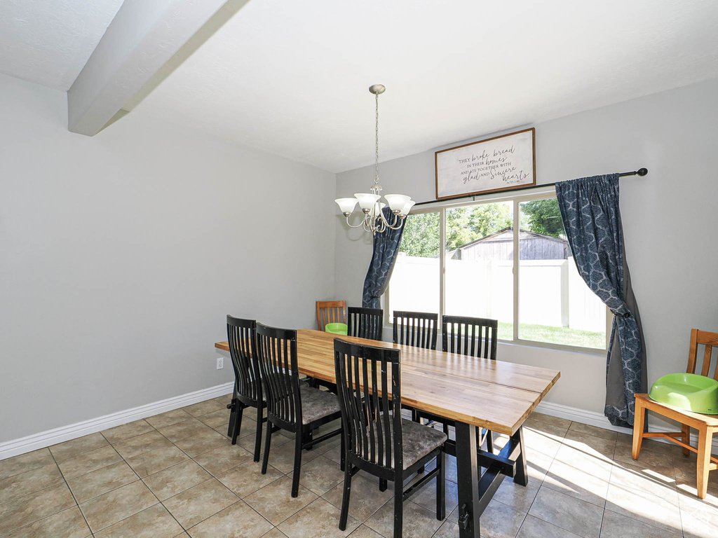 Dining area with a chandelier, light tile patterned flooring, and baseboards