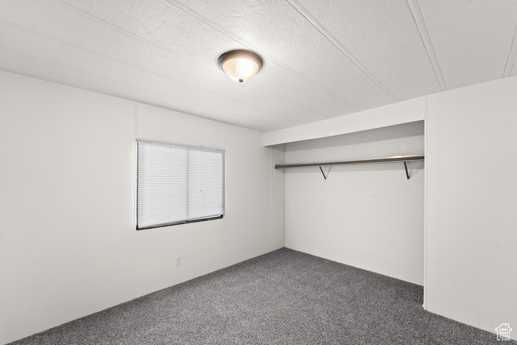 Unfurnished bedroom with carpet flooring, a textured ceiling, and a closet
