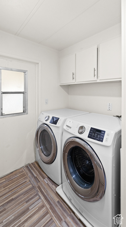 Laundry room with cabinet space, washing machine and dryer, and light wood finished floors