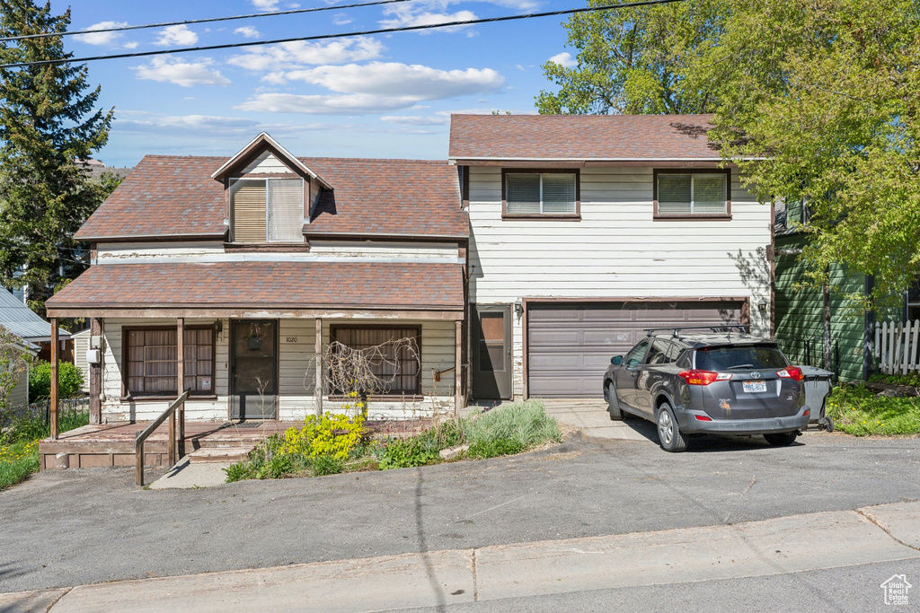 View of front of property with driveway, a porch, a garage, and roof with shingles