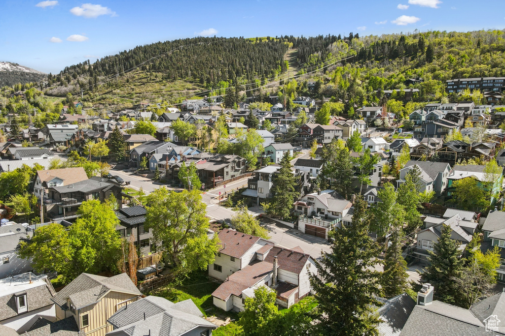 Aerial view of property and surrounding area with nearby suburban area and a heavily wooded area
