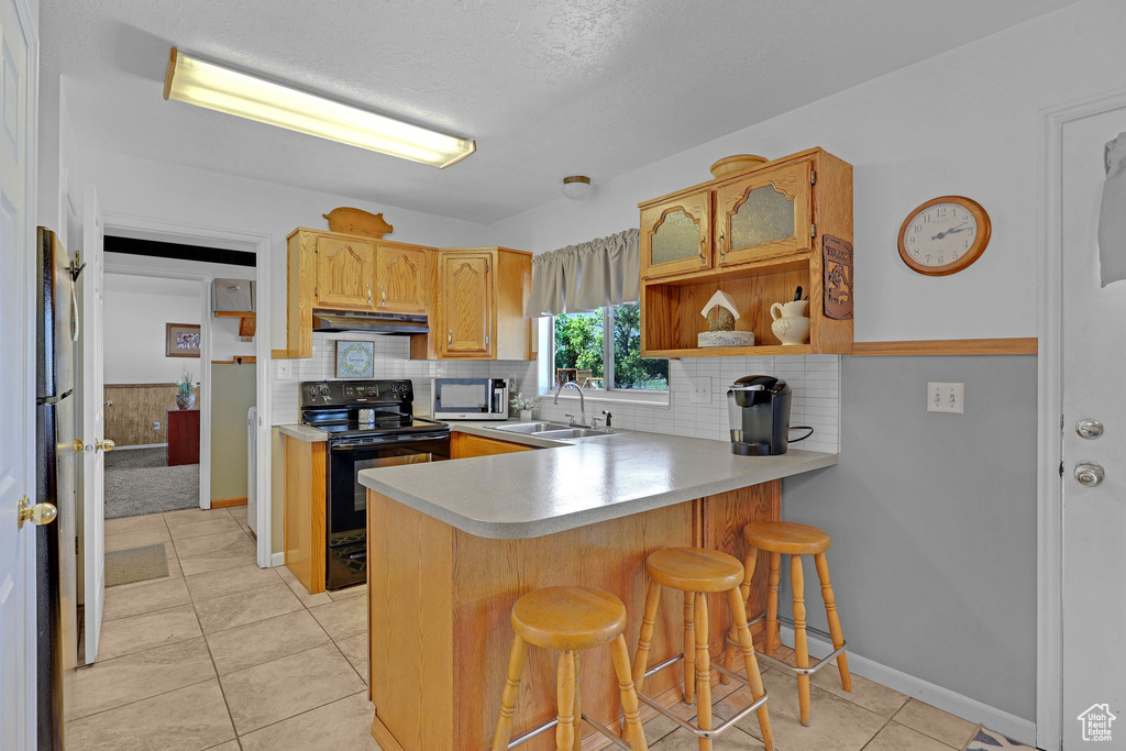 Kitchen with electric range, under cabinet range hood, a sink, a peninsula, and open shelves