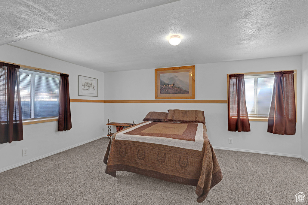 Carpeted bedroom featuring a textured ceiling and baseboards