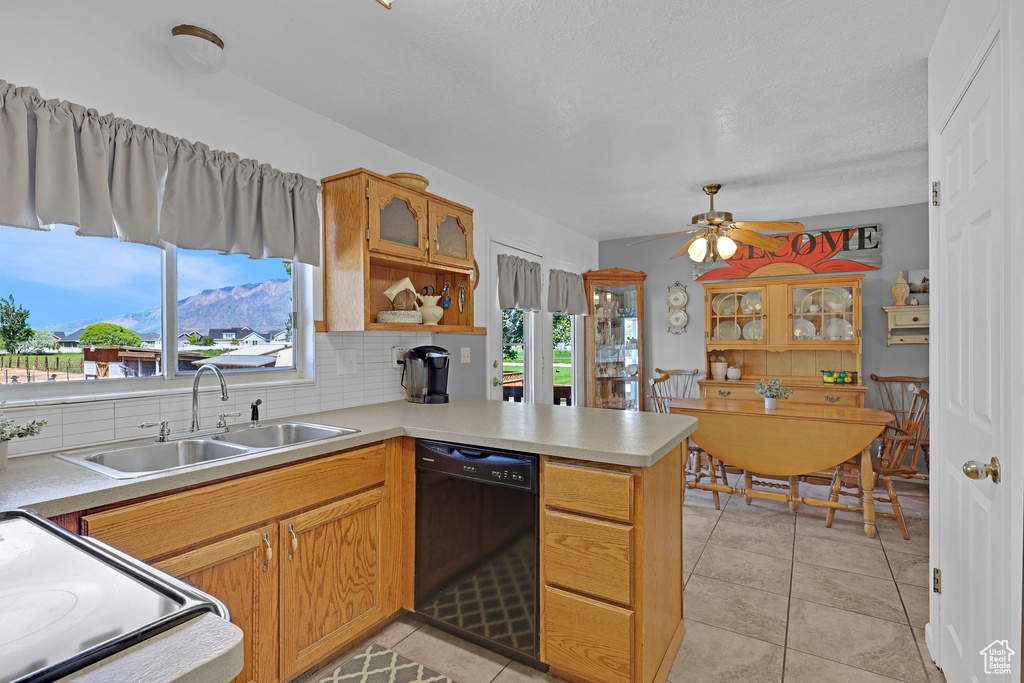 Kitchen featuring black dishwasher, a sink, electric range, a peninsula, and light countertops