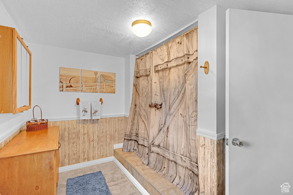 Bathroom with a textured ceiling and wooden walls