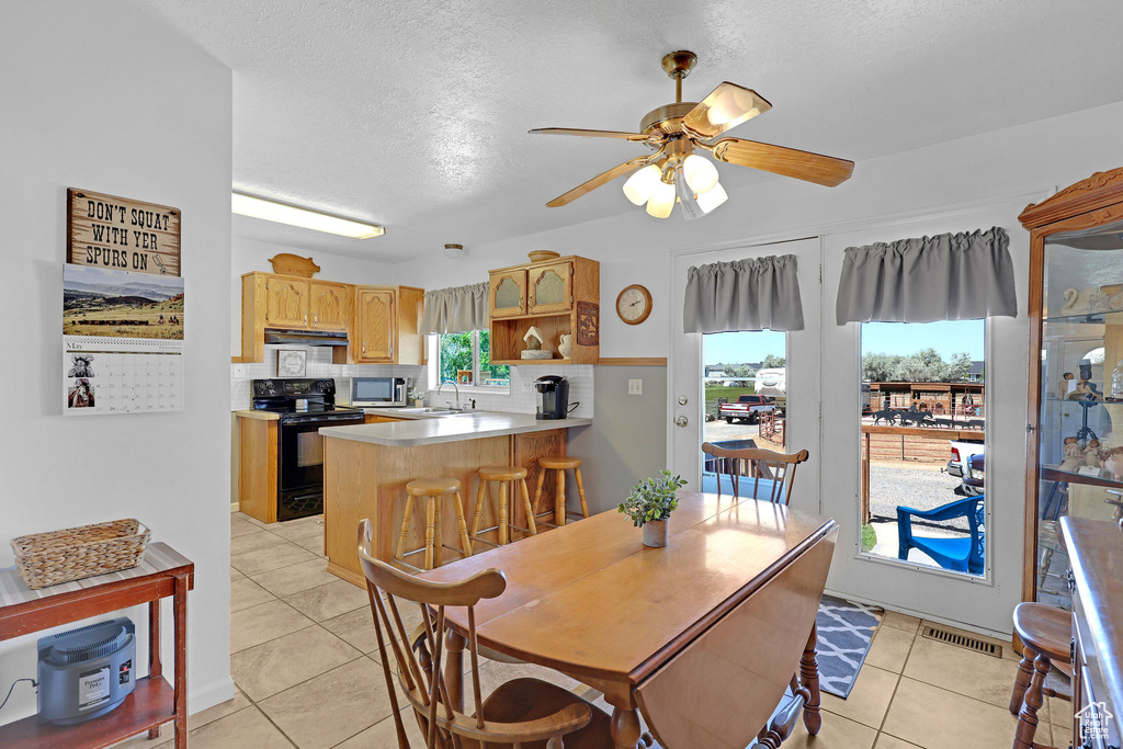 Dining room with light tile patterned flooring, ceiling fan, and a textured ceiling