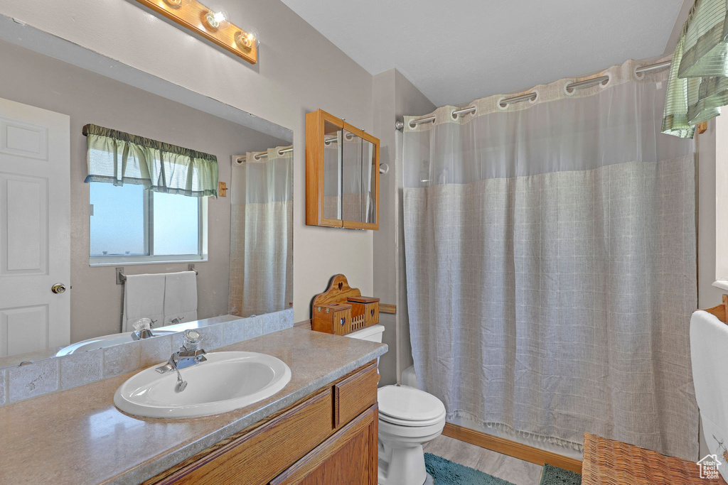 Bathroom with vanity, toilet, and shower / tub combo with curtain