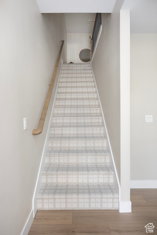 Stairway with wood finished floors and baseboards