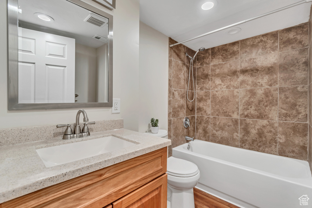 Bathroom with toilet, vanity, shower / bath combination, recessed lighting, and wood finished floors
