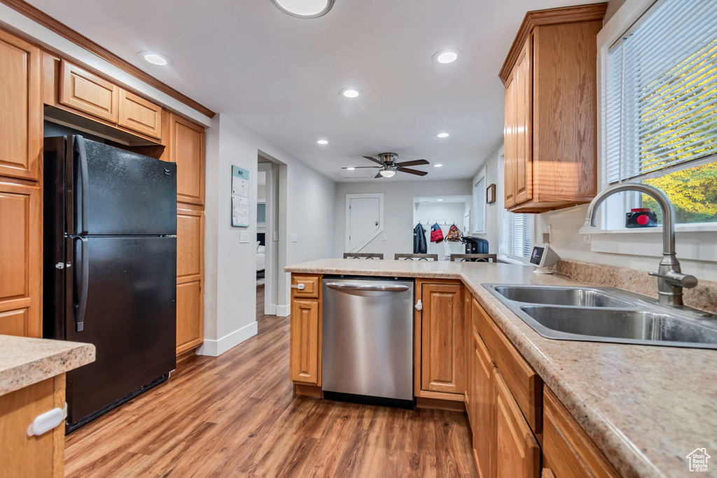 Kitchen with stainless steel dishwasher, freestanding refrigerator, a sink, light wood-style flooring, and recessed lighting