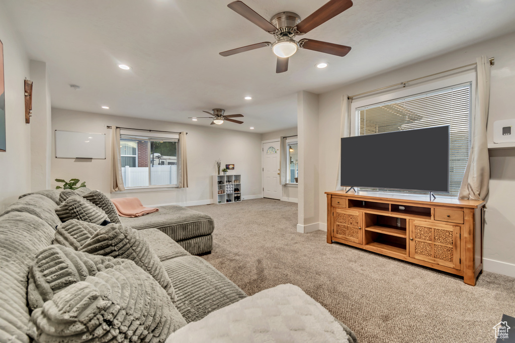 Carpeted living room featuring ceiling fan, baseboards, recessed lighting, and plenty of natural light