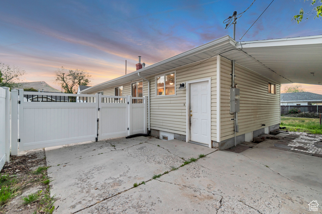 Property exterior at dusk featuring a gate, a carport, and a chimney