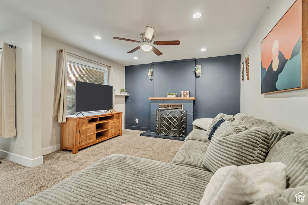 Living room featuring carpet flooring, recessed lighting, ceiling fan, baseboards, and a fireplace with raised hearth