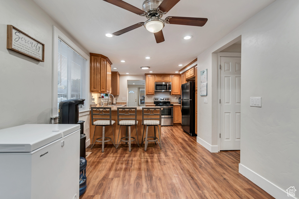 Kitchen featuring stainless steel appliances, ceiling fan, wood finished floors, a peninsula, and recessed lighting