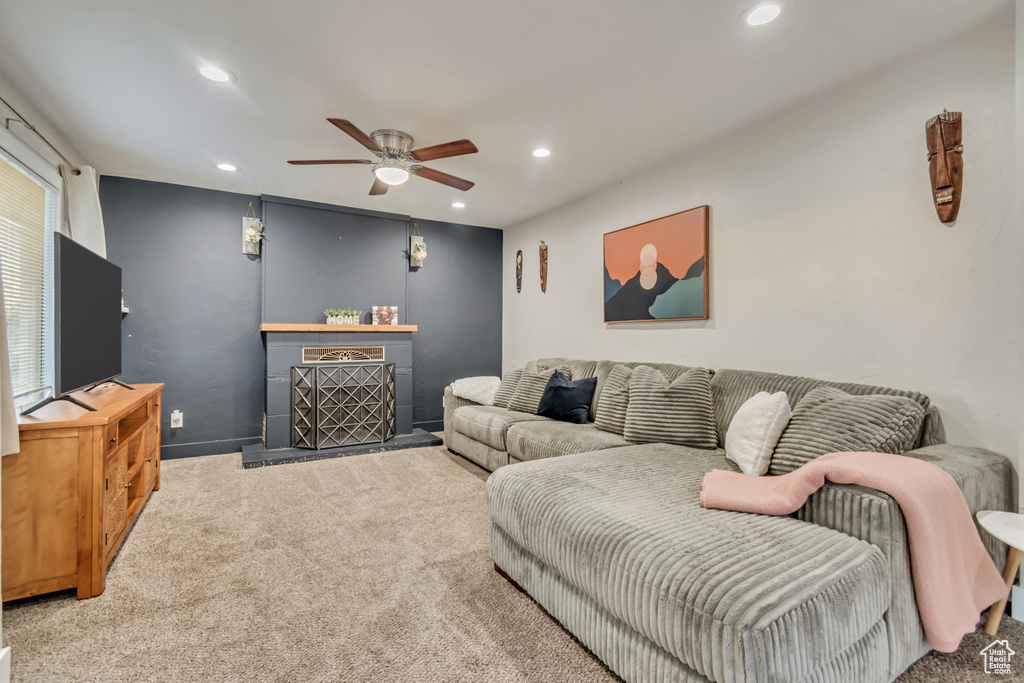 Carpeted living area featuring ceiling fan, recessed lighting, and a fireplace with raised hearth