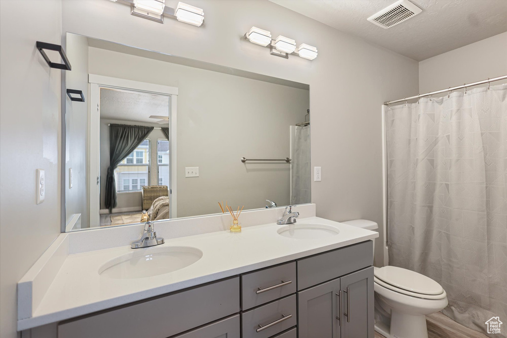Bathroom with double vanity, toilet, and curtained shower