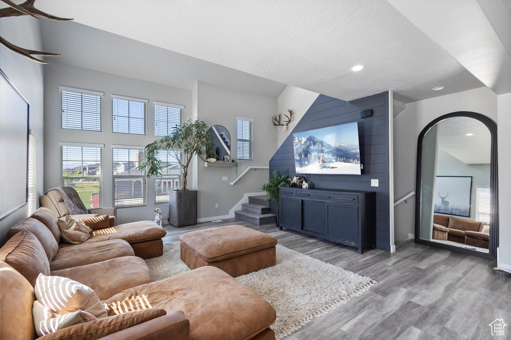 Living area featuring light wood-style floors, baseboards, recessed lighting, and stairs