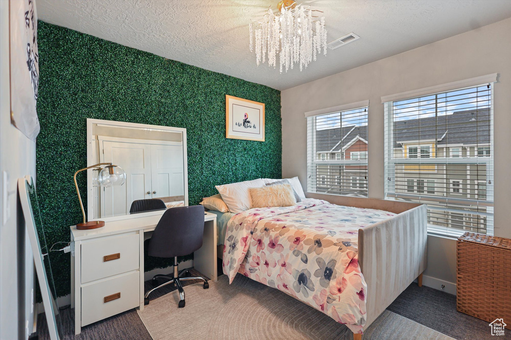 Bedroom with a chandelier, wallpapered walls, an office area, baseboards, and a textured ceiling