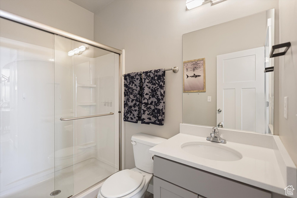 Bathroom featuring toilet, a shower stall, and vanity