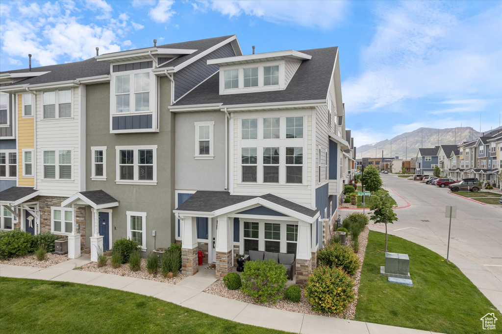 Townhome / multi-family property featuring a mountain view, stone siding, a residential view, and a front lawn