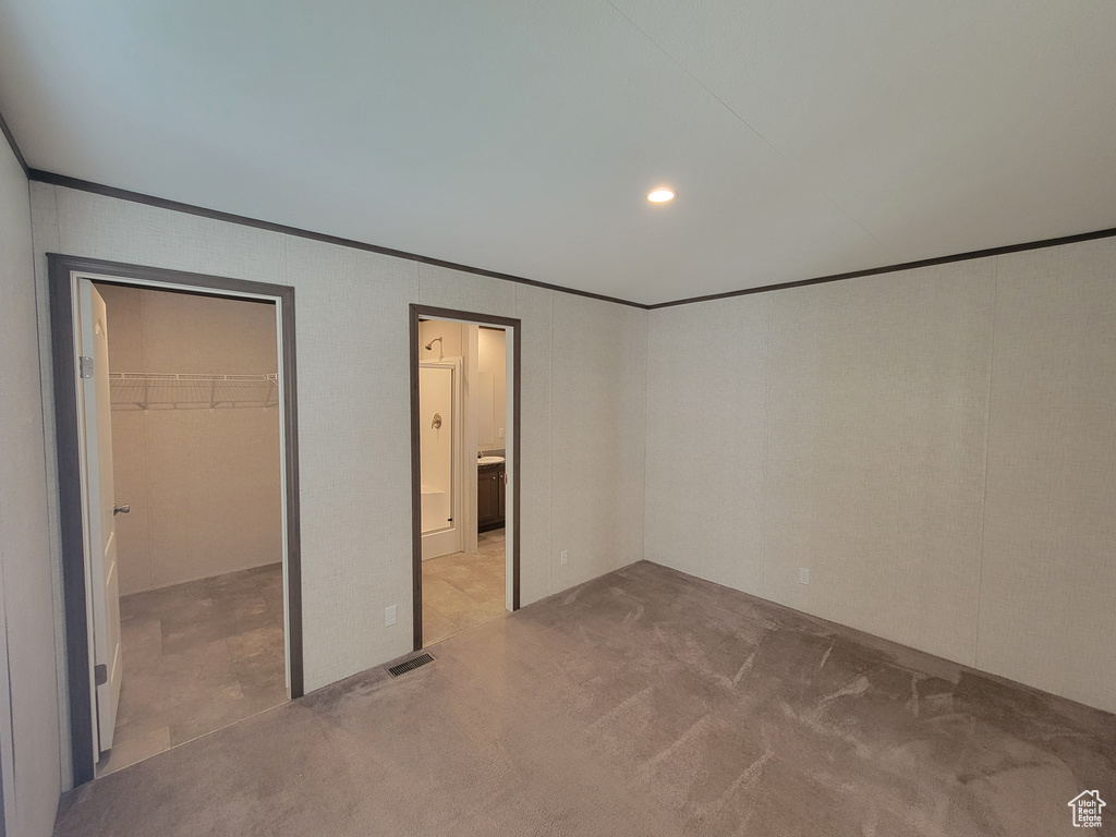 Unfurnished bedroom with crown molding, carpet floors, a spacious closet, recessed lighting, and ensuite bathroom