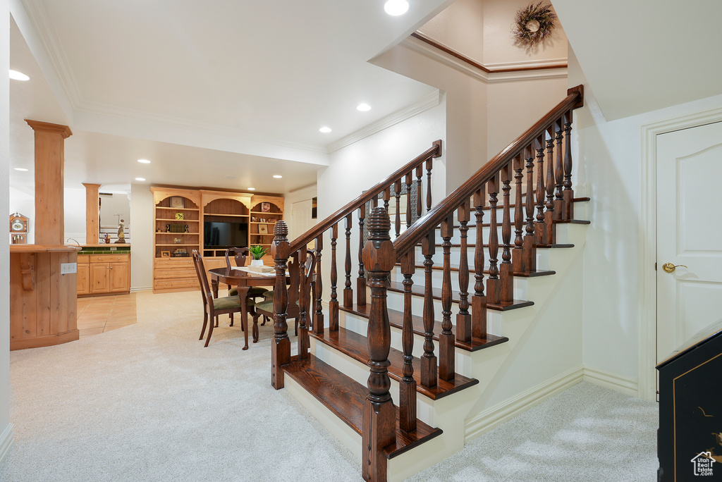 Staircase featuring carpet, crown molding, decorative columns, recessed lighting, and baseboards