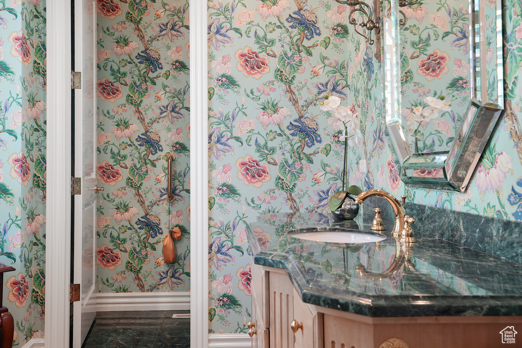 Bathroom with vanity, wallpapered walls, and baseboards