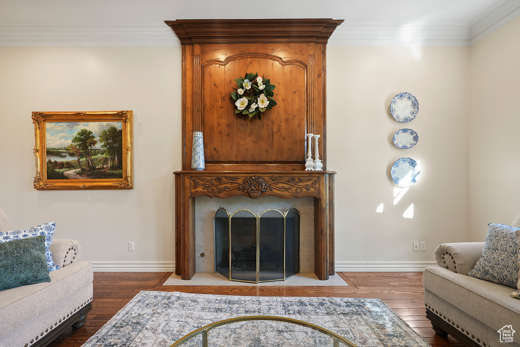 Living area featuring wood finished floors, a fireplace with flush hearth, crown molding, and baseboards