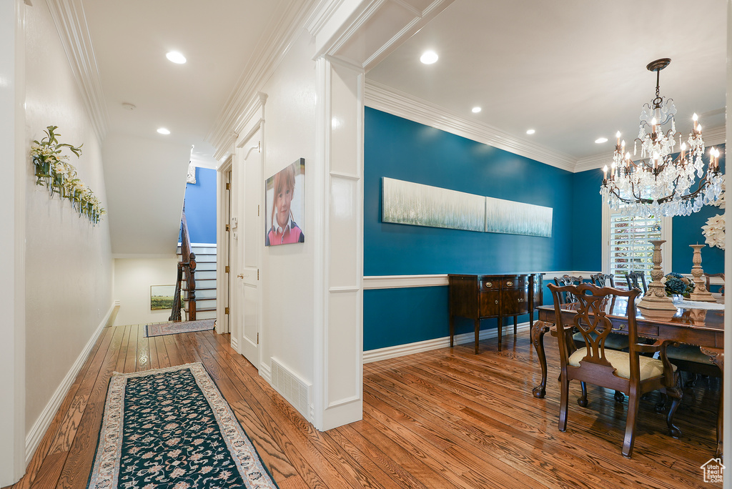 Dining room featuring hardwood / wood-style flooring, a chandelier, recessed lighting, baseboards, and ornamental molding