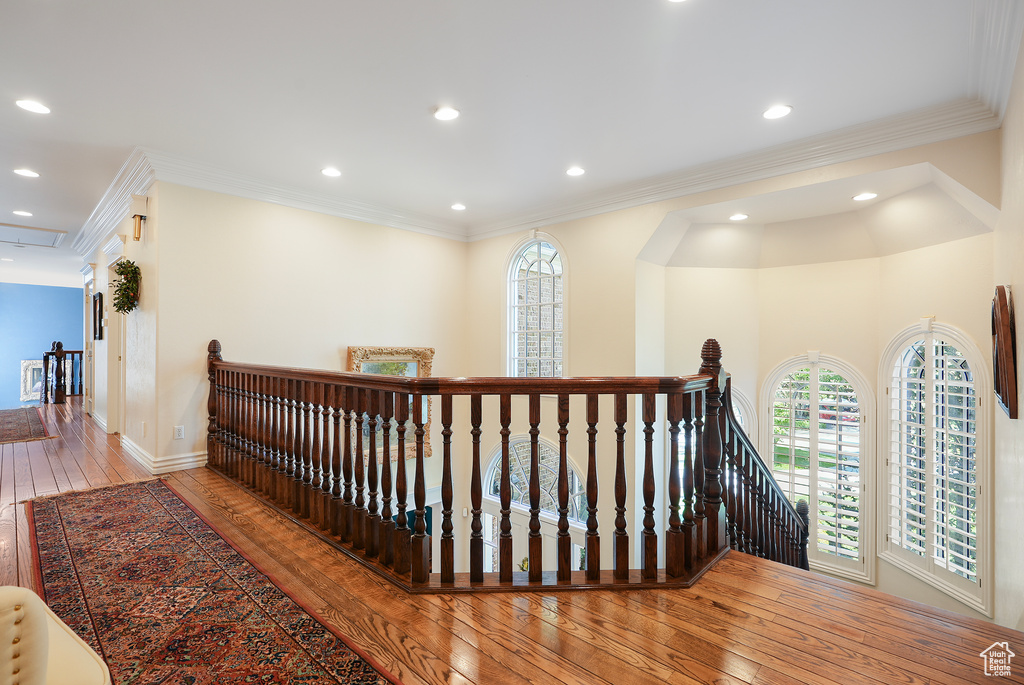 Hallway with an upstairs landing, wood-type flooring, recessed lighting, ornamental molding, and baseboards