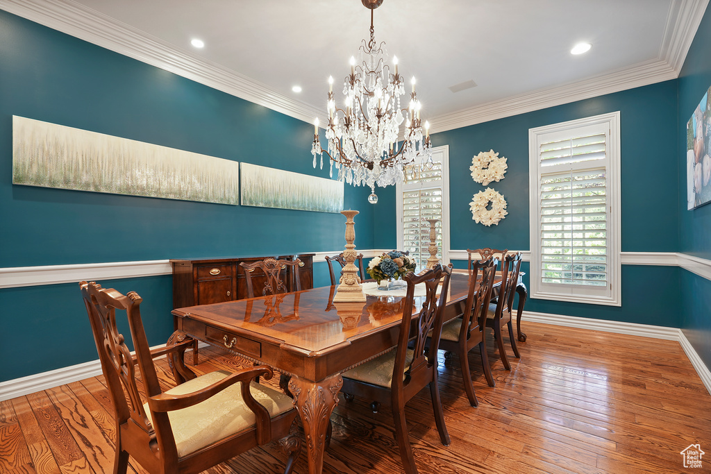 Dining space featuring a chandelier, wood-type flooring, baseboards, recessed lighting, and ornamental molding