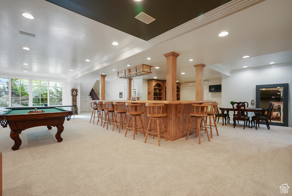 Recreation room featuring ornamental molding, light colored carpet, decorative columns, bar area, and billiards table